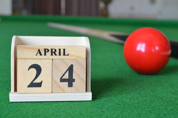 April 24, number cube with balls on snooker table, sport background.