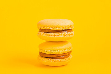Sweet almond colorful yellow macaron or macaroon dessert cake isolated on trendy yellow modern fashion background. French sweet cookie. Minimal food bakery concept. Copy space