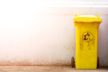 old and dirty yellow plastic garbage bin in public.