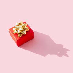 Shot of small red gift of pastel pink background. Holiday concept new year or Christmas gift box presents Xmas. Minimal composition. Flat lay. Top view. Copy space.
