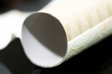 Empty toilet paper carboard roll close up macro shot on dark background.