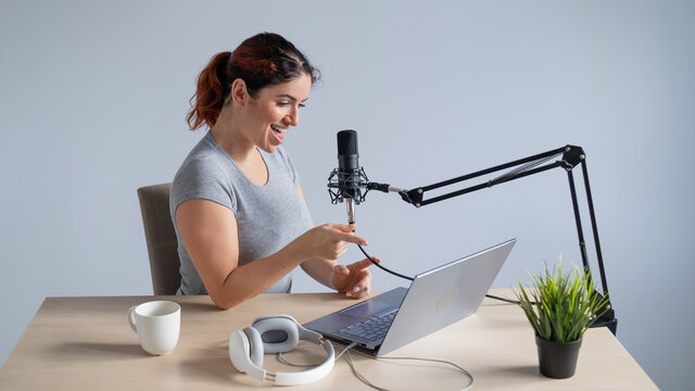 A charming woman radio host is broadcasting live on a laptop. Online radio concept