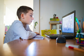 Child at home having remote school on laptop computer.