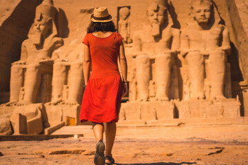 A young tourist in a red dress entering the Abu Simbel Temple in southern Egypt in Nubia next to Lake Nasser. Temple of Pharaoh Ramses II