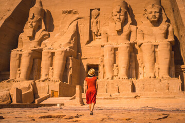 A young tourist in a red dress entering the Abu Simbel Temple in southern Egypt in Nubia next to Lake Nasser. Temple of Pharaoh Ramses II