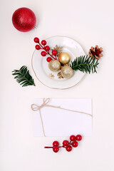 sobre blanco de invitación con adornos de navidad alrededor y en un plato