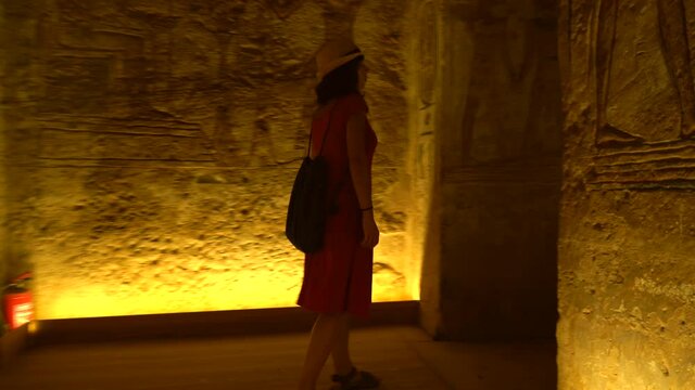 A young woman walking out of the beautiful temple of Abu Simbel from the inside out until the pharaohs are seen, in southern Egypt in Nubia next to Lake Nasser. Temple of Pharaoh Ramses II, 4k video