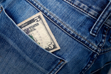 Dollar bill in the back pocket of jeans. 5 bucks in a denim pocket.