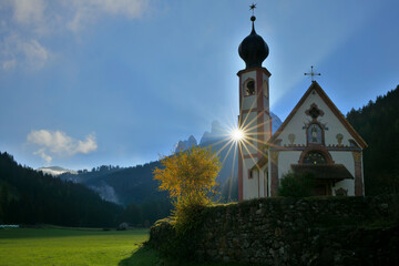 Sonnenstrahlen in den herbstlichen Dolomiten mit kleiner Kapelle
