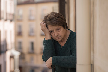 dramatic lifestyle portrait of mature woman on her 70s crying depressed and sad at home balcony feeling desperate suffering anxiety problem in senior female depression