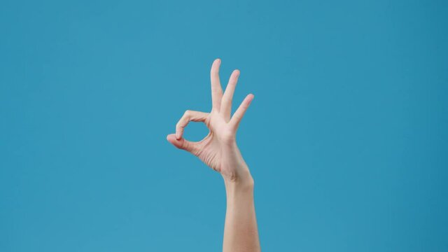 Young woman hand showing ok sign with fingers isolated over blue background in studio. Copy space for place a text, message for advertisement. Advertising area, mock up promotional content. Close up.