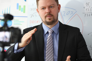 Male in suit and tie show stats graph pad making promo videoblog or photo in office camcorder to...
