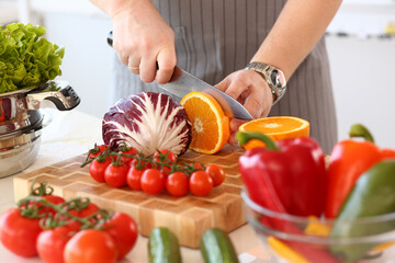 Chef Chop Juicy Orange Fruit Kitchen Photography. Vegan Cut Citrus with Knife in Hands. Healthy Vegetable Ingredient for Salad. Fresh Tomatoes, Cabbage and Pepper in Bowl. Culinary Blog Closeup Shot