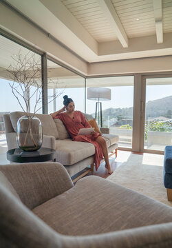Woman relaxing with digital tablet on sofa in luxury living room