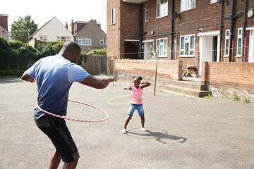 Father and daughter playing with plastic hoops in sunny neighborhood
