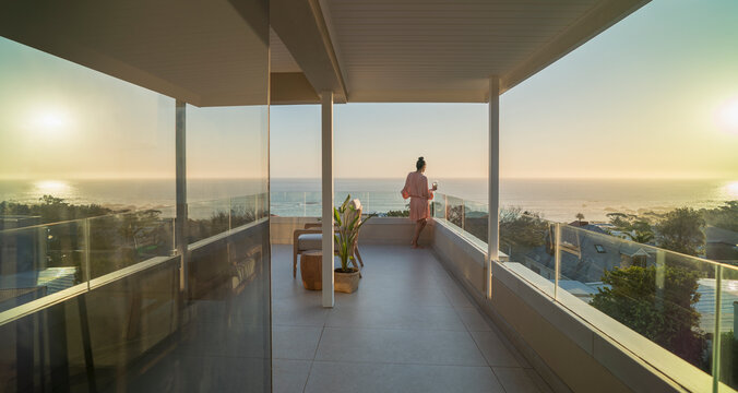 Woman relaxing on sunny balcony with sunset ocean view