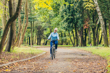 Obraz premium senior woman walking in the park with a bicycle, sunny day
