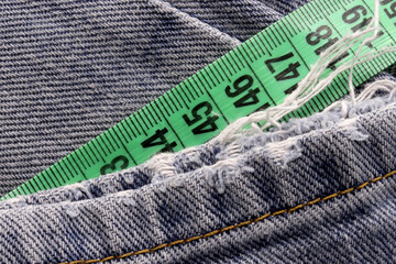 green measuring tape on blue jean texture