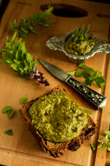 frisches basilikum pesto auf herzhaften bauernbrot auf einem holzbrett