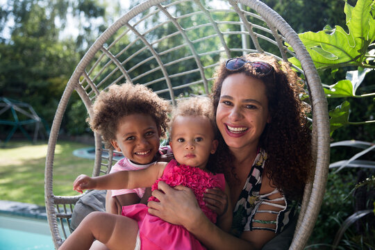 Portrait happy mother and daughters in summer swing chair