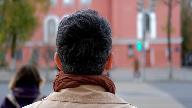 A man waits for a traffic light and crosses the road when the light turns green. Crossing the road according to the traffic rules.