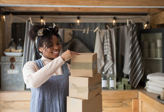 Smiling female shop owner with stack of cardboard boxes