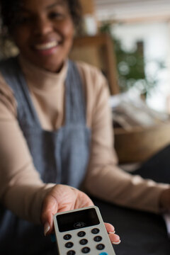 POV female shop owner holding credit card reader for customer