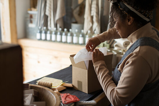 Female shop owner preparing package at shop counter