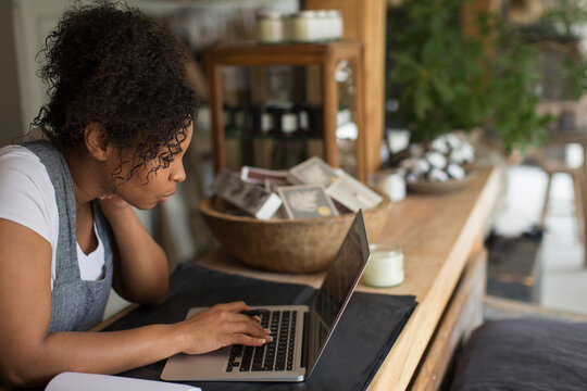 Female shop owner using laptop at shop counter
