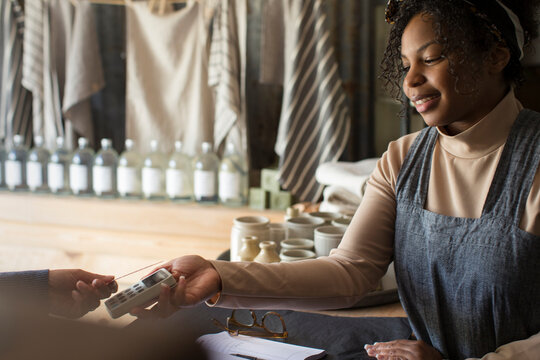 Female shop owner holding credit card reader for customer at counter