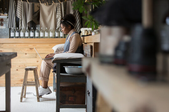 Female shop owner using laptop on bench