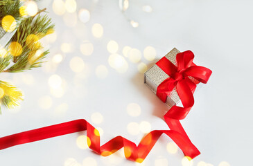 Gift box with red ribbon on white background with bokeh