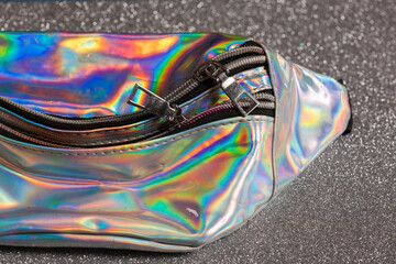 Selected focus of Zipper on a neon holographic color bag on the bokeh silver background.