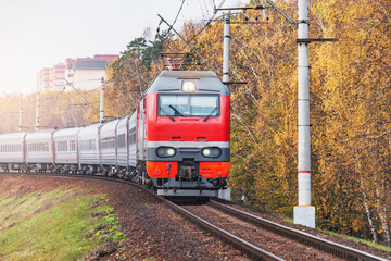 Naklejka premium Passenger train moves by the autumn forest.