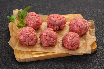 Raw meatball over wooden background