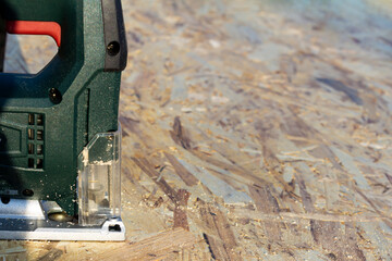 Cutting out an OSB sheet with a jigsaw. Copyspace.