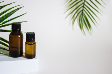 glass brown jars with plant stracts and oils on a light white background. For cosmetics or cosmetology background. stand for advertising beauty products. Plants decor eucalyptus, fern, spruce