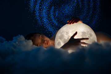 Tender young naked woman sleeps and hugs the moon on amazing starry sky with and soft clouds...