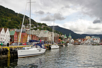 Fototapeta na wymiar Boats and historic buildings along the Bryggen (wharf) in Bergen, Norway under cloudy sky
