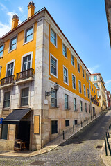 Lisbon Portugal. Yellow building and street with paving stones. Cityscape with blue sky.