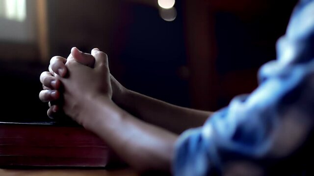 Close up hands praying to God on wooden table in morning, Christian concept.