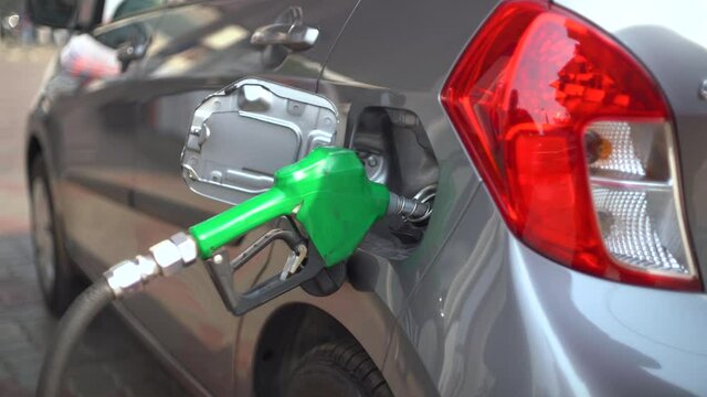 Man at a petrol pump fuel station inserting nozzle into fuel tank of a car and starting the fuel pumping in the auto cut off petro diesel pump