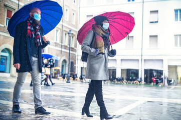People with face mask walking on the street city under an umbrella in rain in the covid-19 time