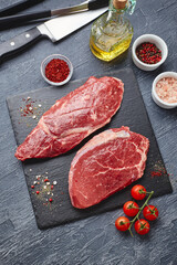 Raw meat beef steak on black top view.