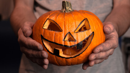 A young man, holds out a halloween pumpkin or jack-o-lantern . The young master made a jack-o-lantern for the Halloween party.