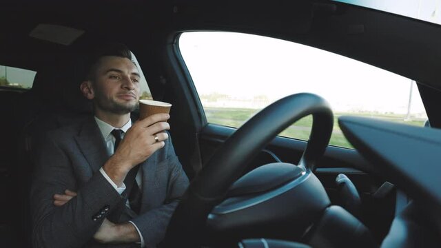 Relaxed Businessman experience to riding an autonomous self driving car and drink a coffee. Vehicle starts autonomous self-driving. Concept of Driverless Future Technology in transport