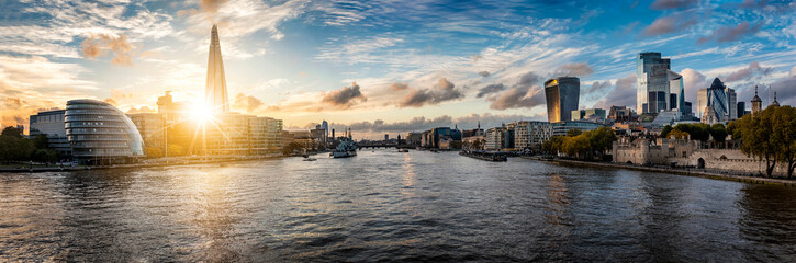 Sunset behind the new skyline of London, United Kingdom, with the reflecting skyscrapers of the City and modern office buildings along the Thames river