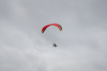 The red paraglider flies in the cloudy sky. Extreme sport