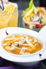 Traditional vegetable soup broth in a white plate on a table in a restaurant.
