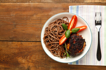 Plate soba with chicken tomatoes and spinach on a napkin next to a fork.